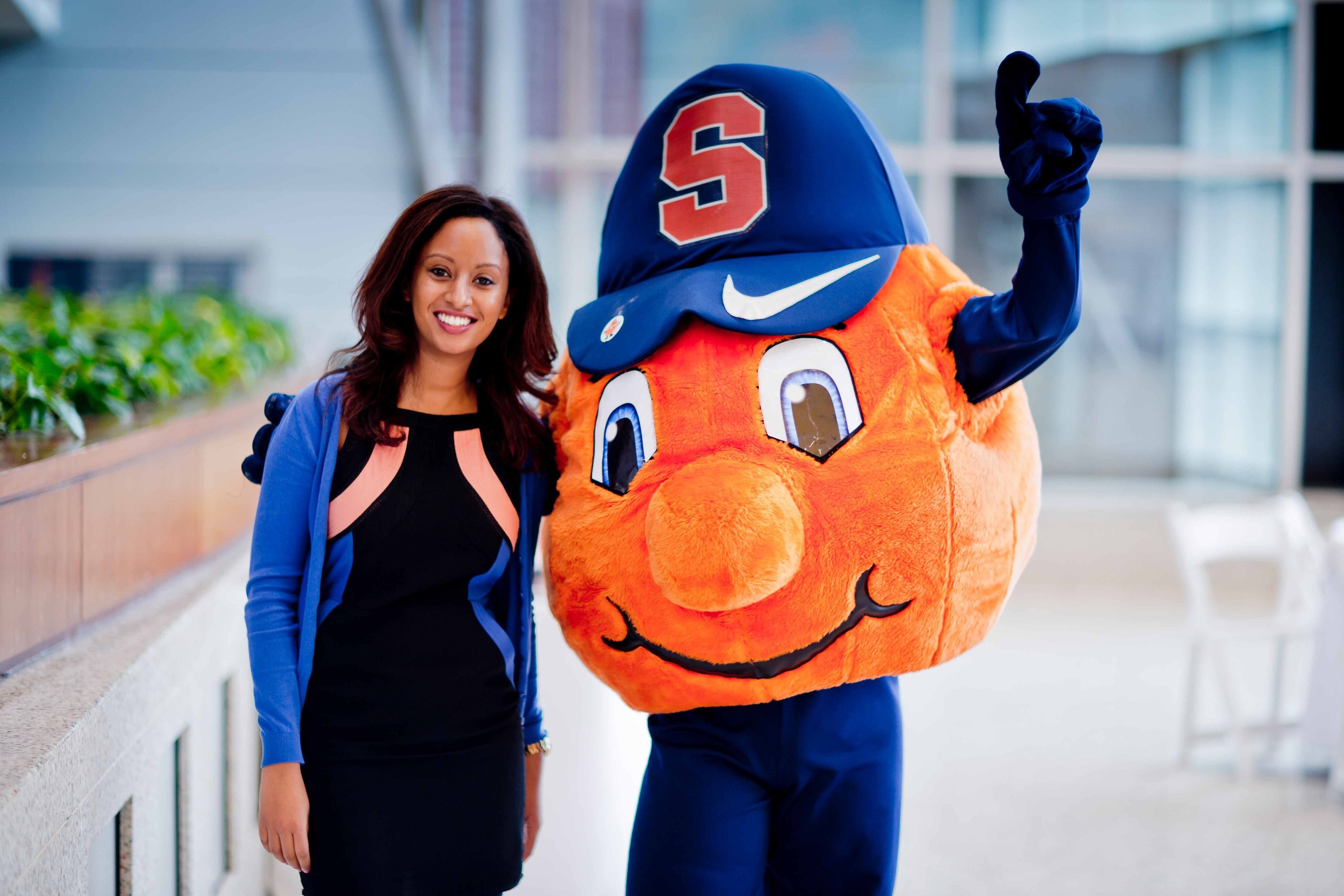 Syracuse University mascot, Otto the Orange, posing with a smiling student