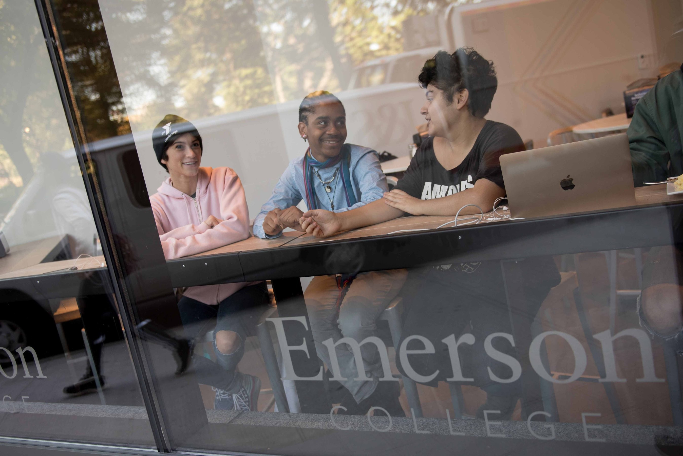 Students at Emerson College socialize next to a window in an academic building