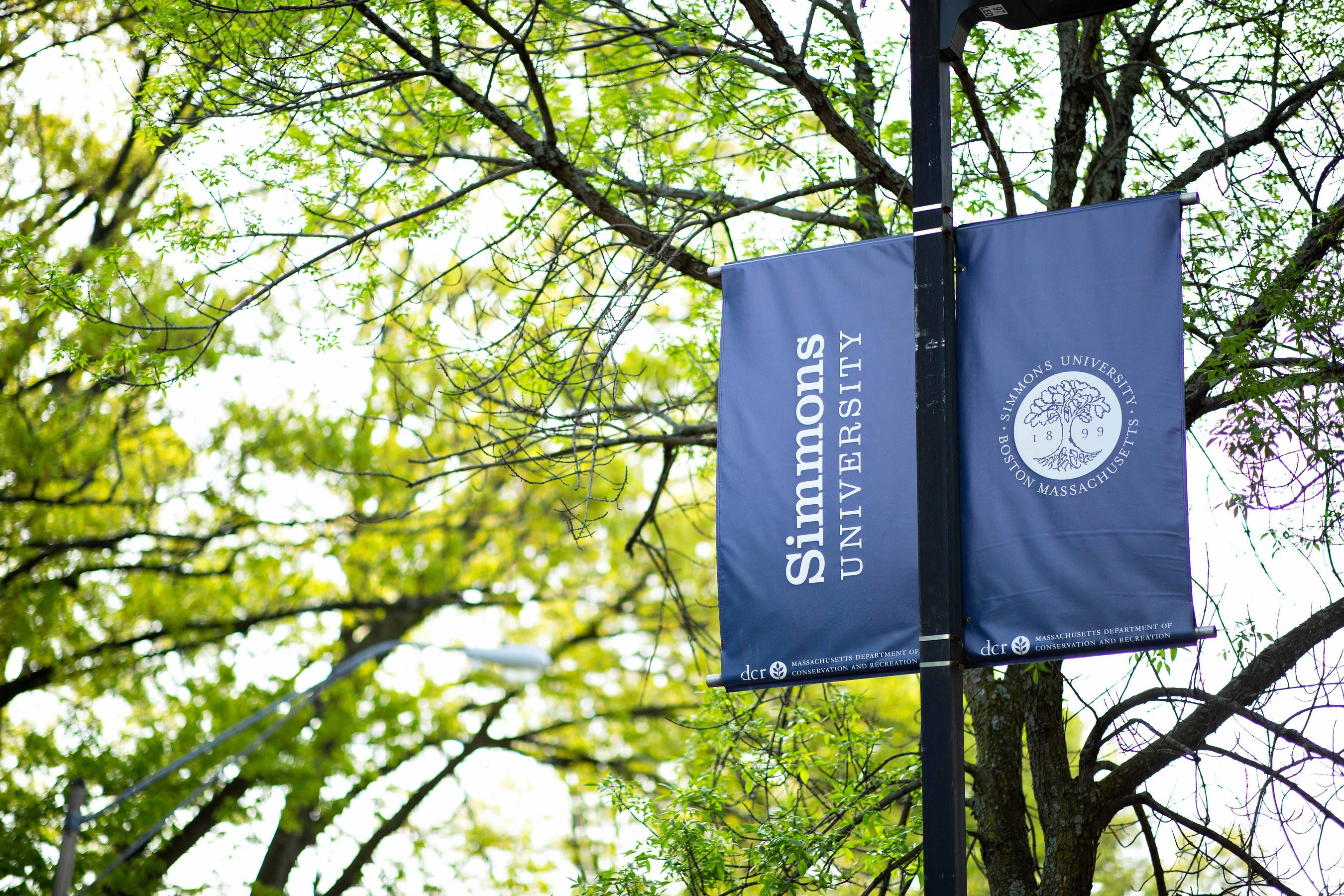 Simmons University flag attached to a light pole on campus