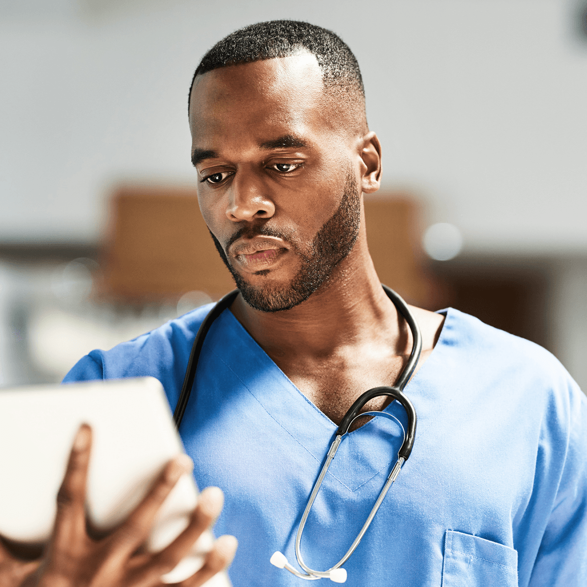 Man in scrubs looking at tablet