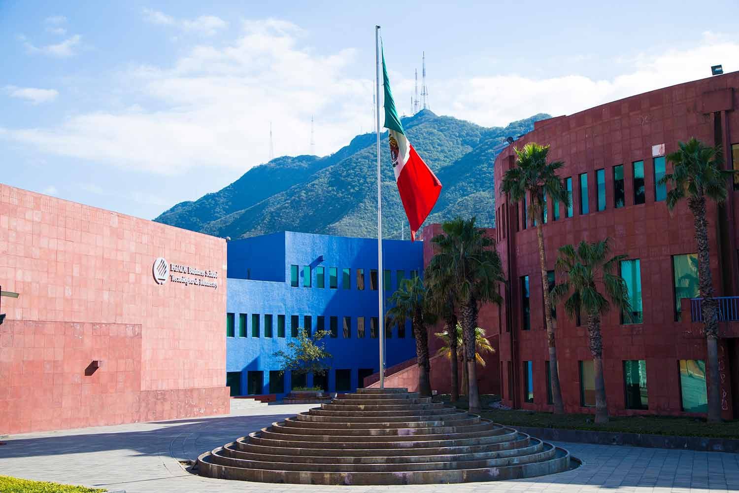 The Mexican flag waves outside the main building of the EGADE Business School with a green mountainside in the background