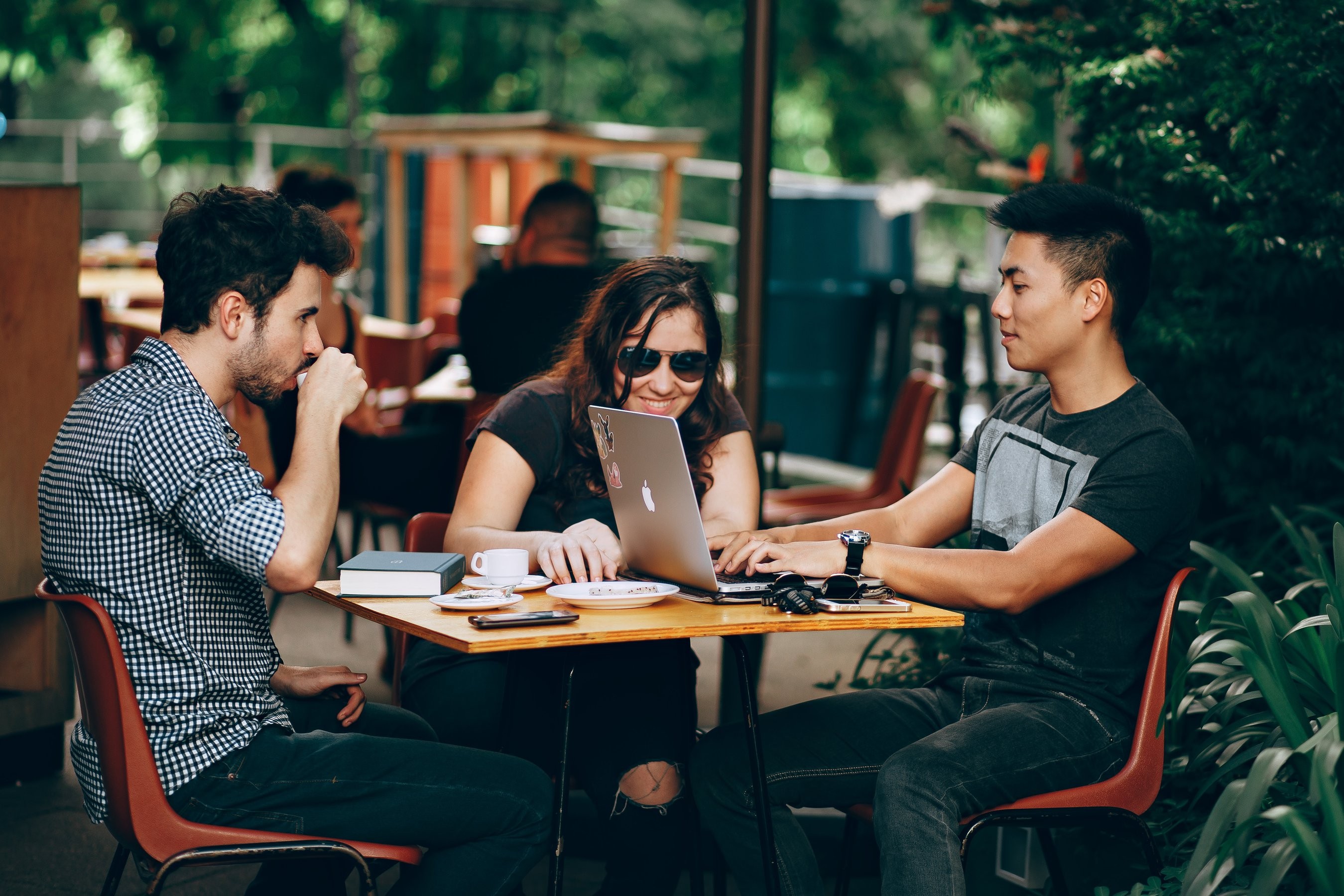 Three students sitting outside at a coffee shop studying