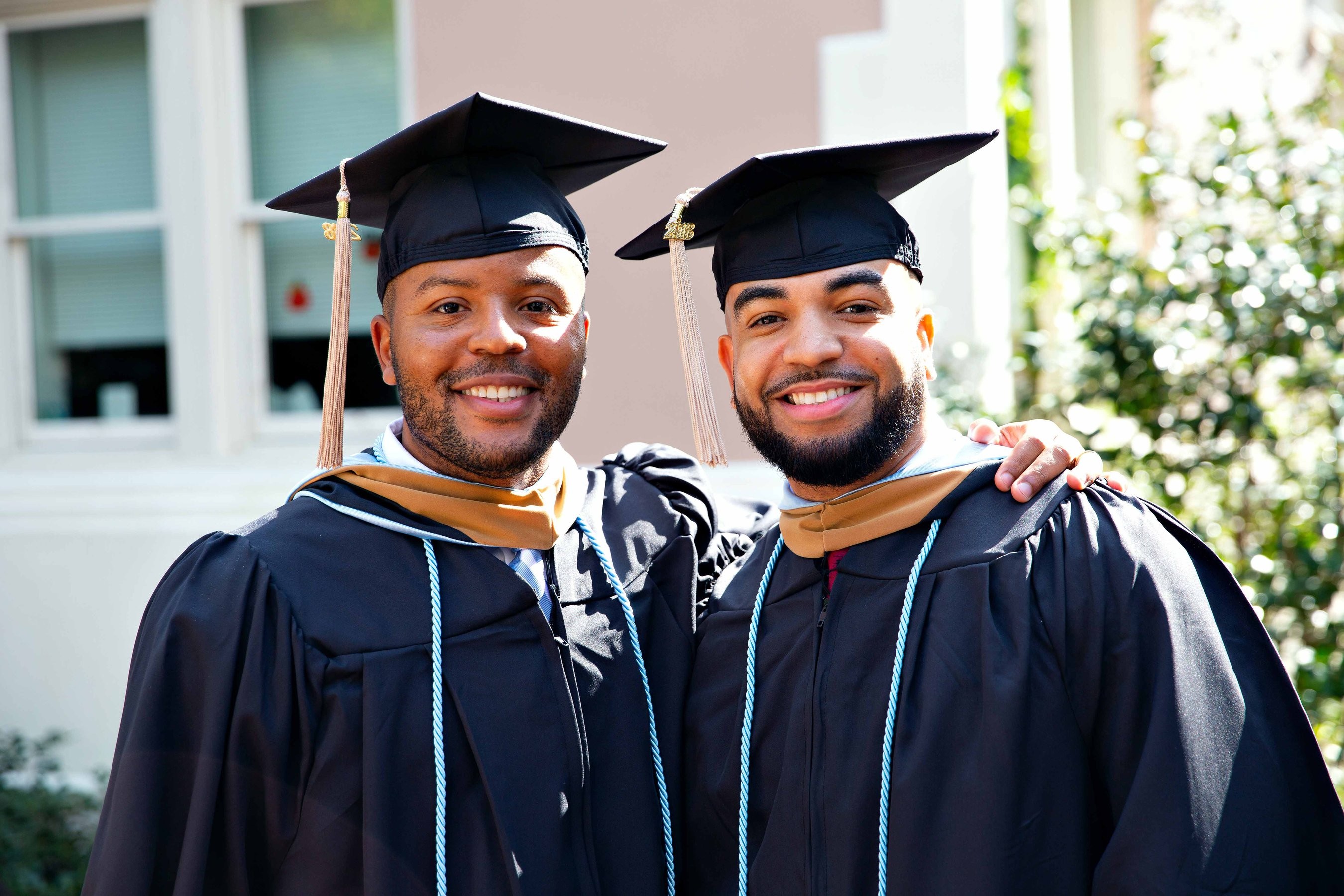Two MBA students posing for a photo in their cap and gowns on graduation day