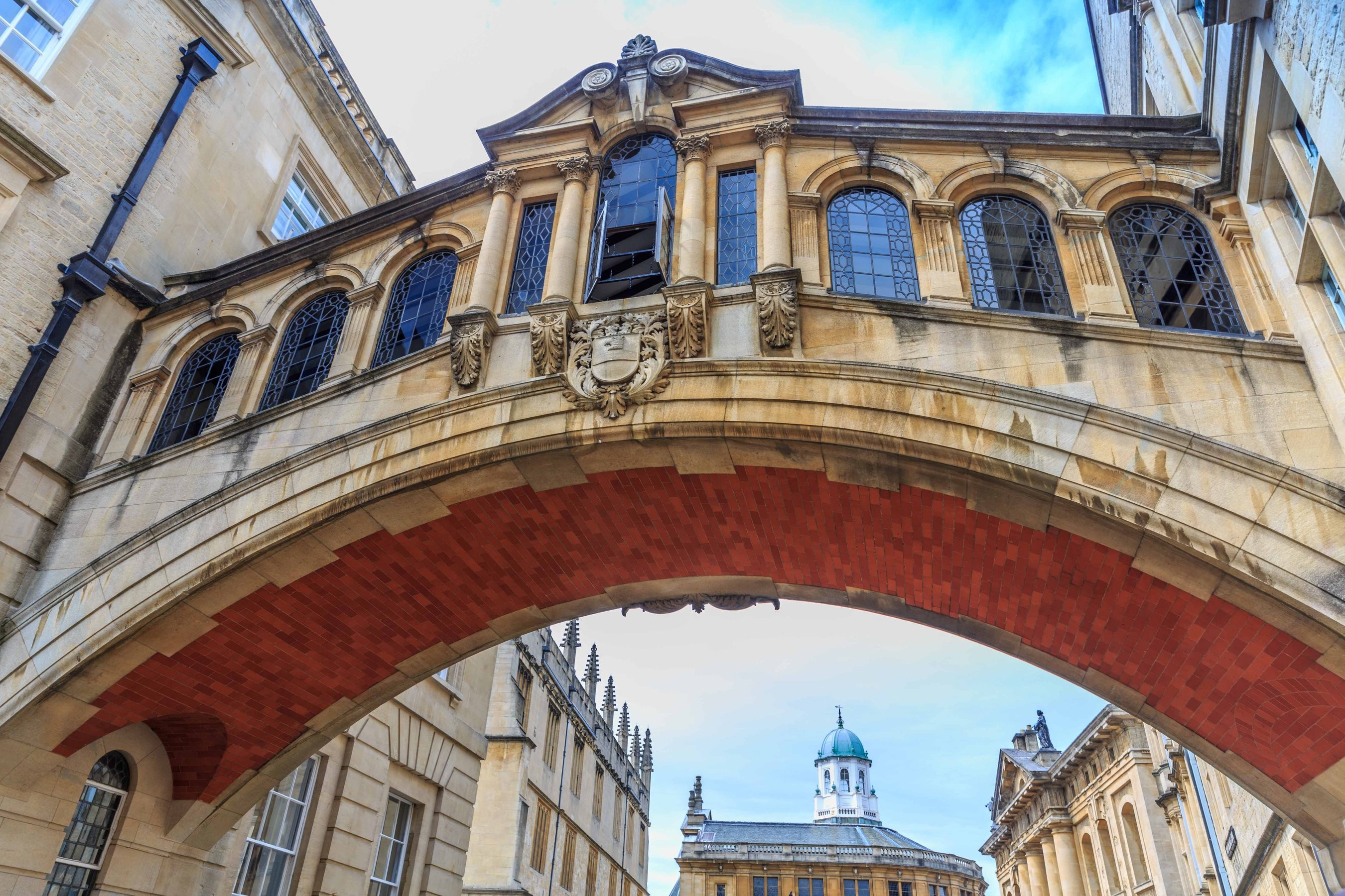 An arched walkway with windows connecting two buildings on the Oxford University campus