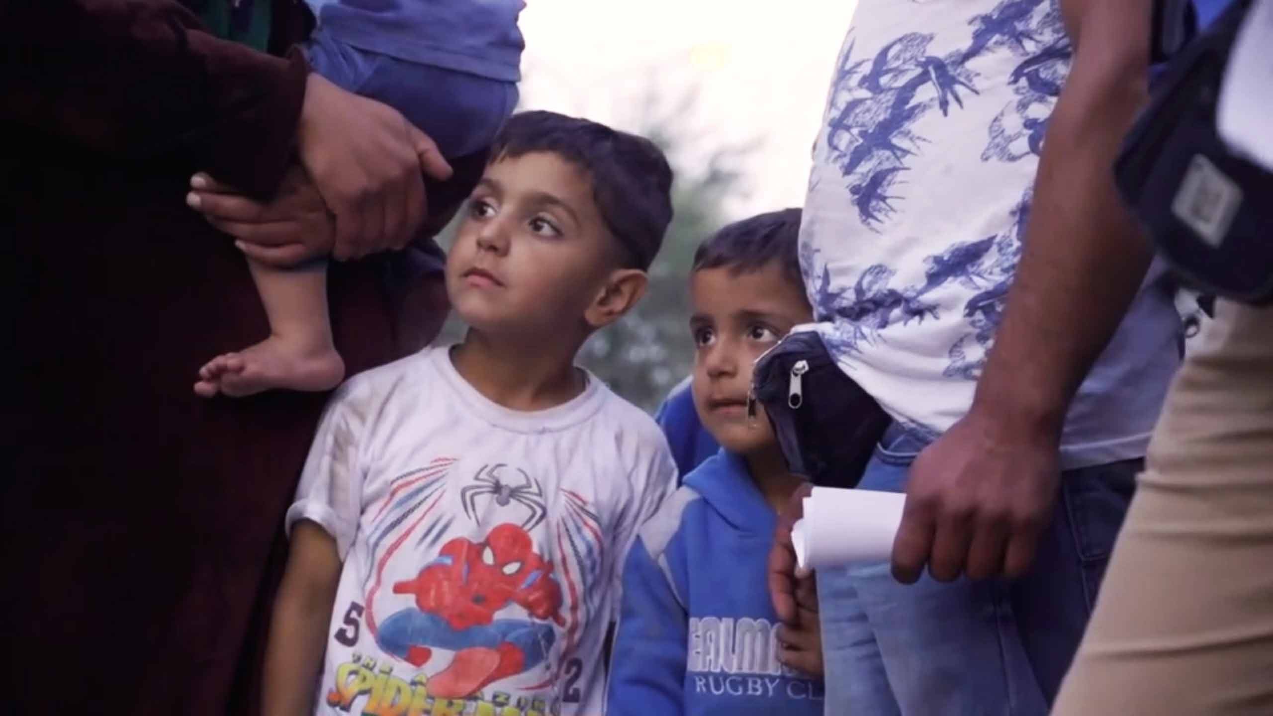 Two young boys look on as rescue services assist their community