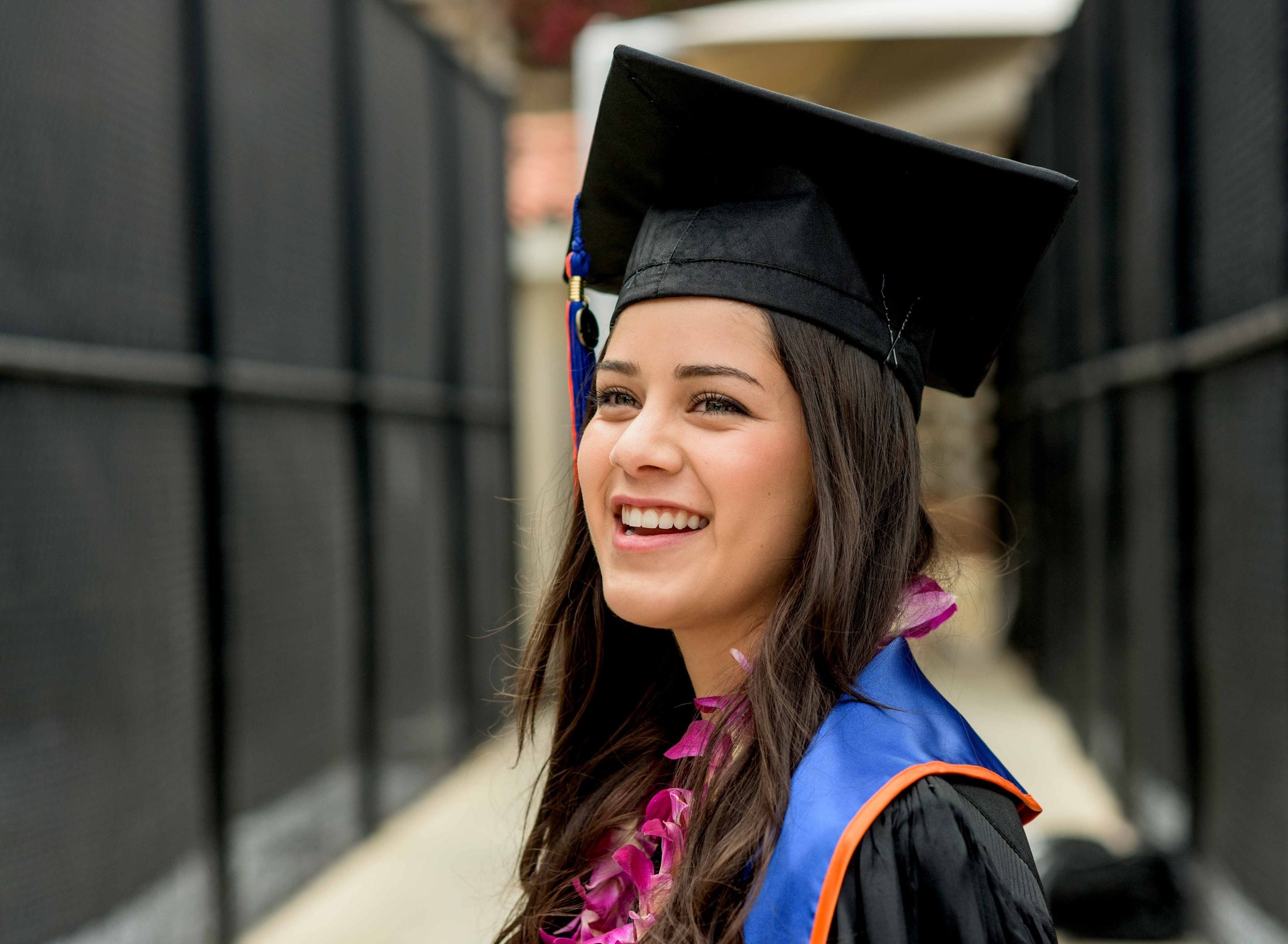 A Pepperdine University graduate smiles for a photo in her cap and gown